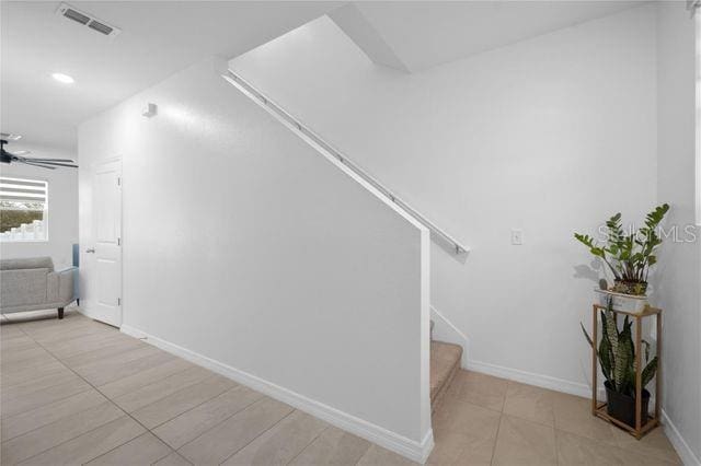 staircase featuring tile patterned flooring and ceiling fan