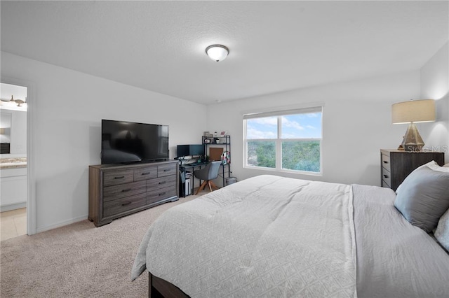 bedroom with ensuite bathroom and light colored carpet