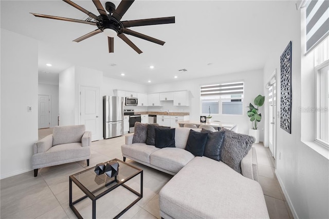 tiled living room with ceiling fan and sink