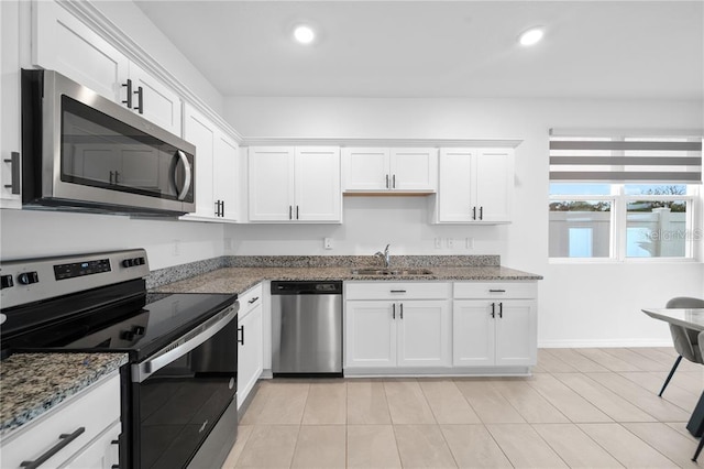 kitchen featuring white cabinets, appliances with stainless steel finishes, dark stone counters, and sink