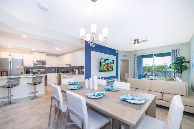 tiled dining space featuring ceiling fan with notable chandelier and sink