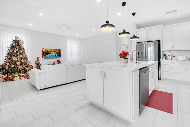 kitchen featuring a center island with sink, white cabinets, stainless steel appliances, and hanging light fixtures