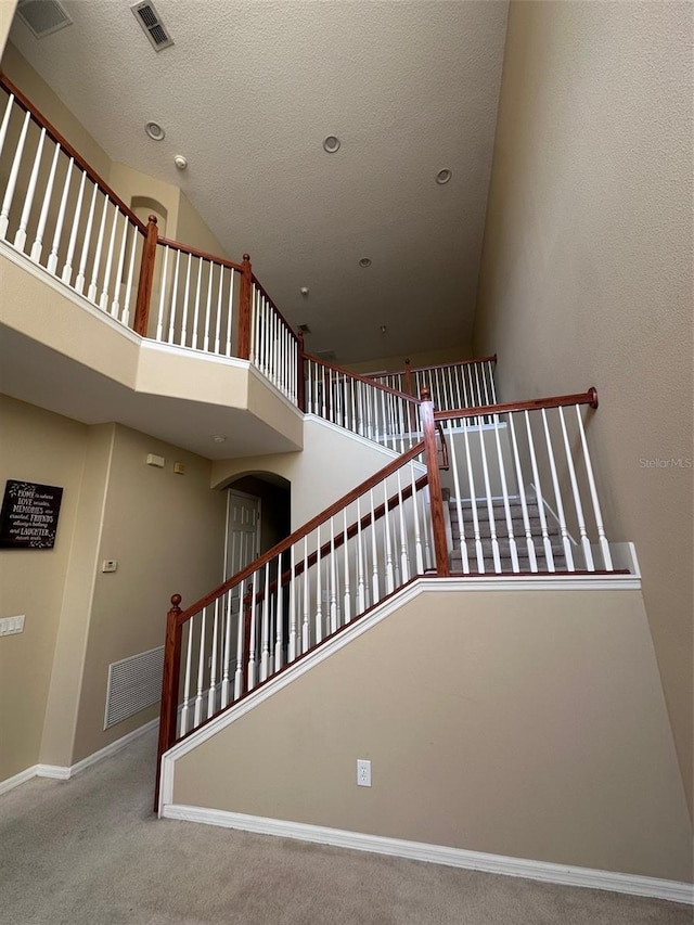 stairs featuring carpet floors and a towering ceiling