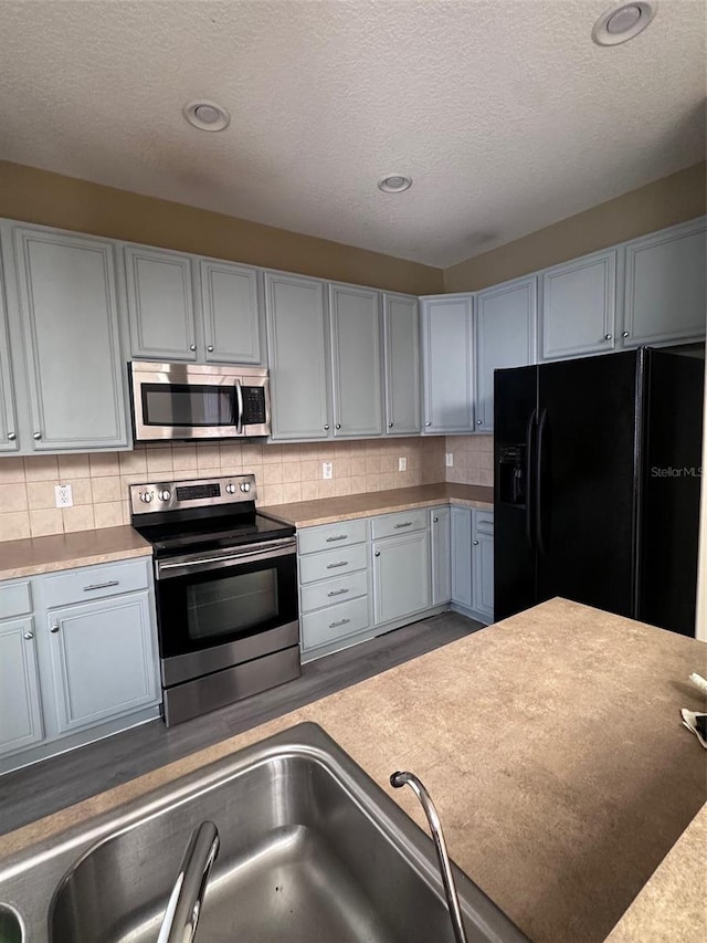 kitchen with a textured ceiling, sink, stainless steel appliances, and tasteful backsplash