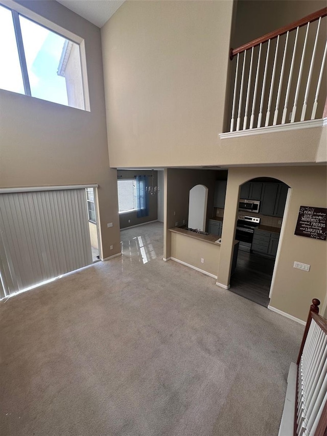 unfurnished living room with carpet flooring, a high ceiling, and a wealth of natural light