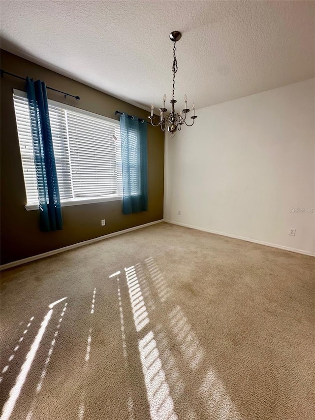 unfurnished room with carpet floors, a textured ceiling, and an inviting chandelier