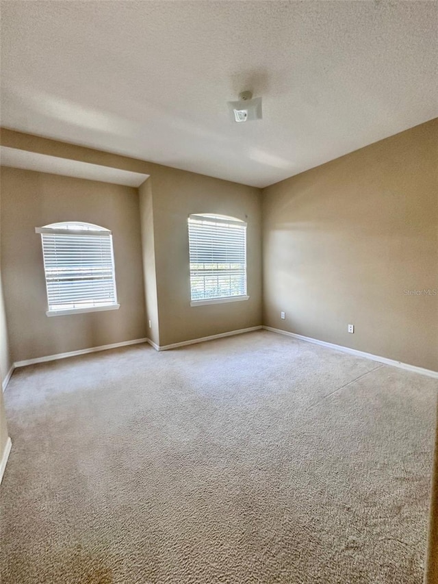 carpeted spare room with a textured ceiling