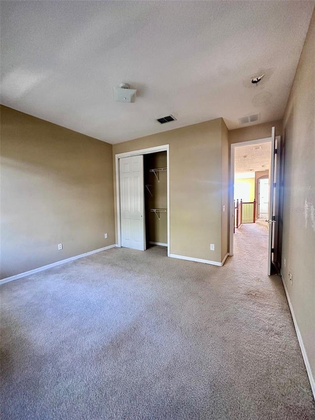 unfurnished bedroom with carpet, a textured ceiling, and a closet