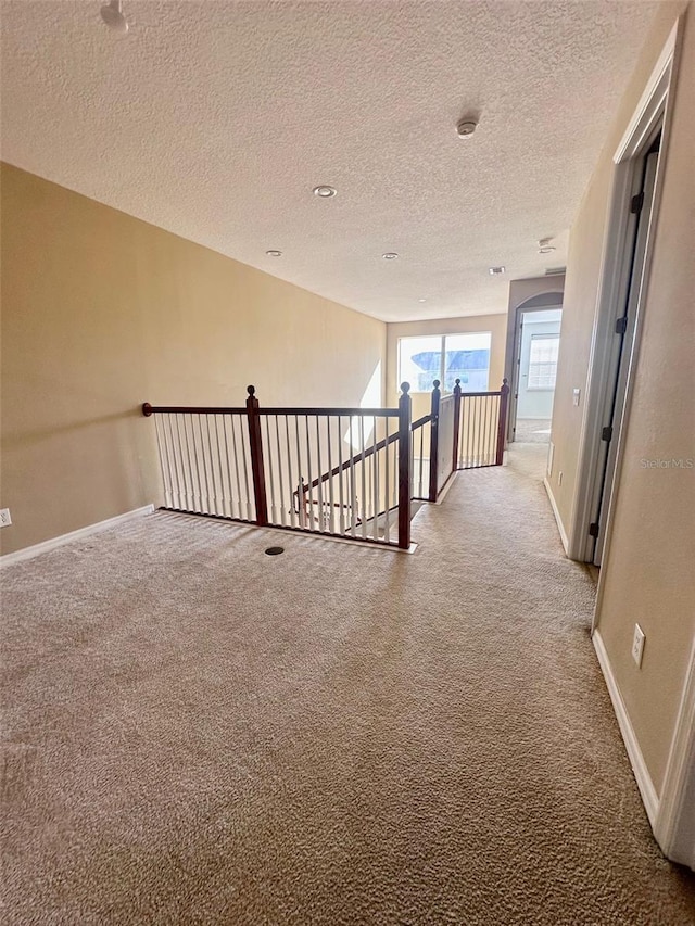 hall featuring a textured ceiling and carpet floors