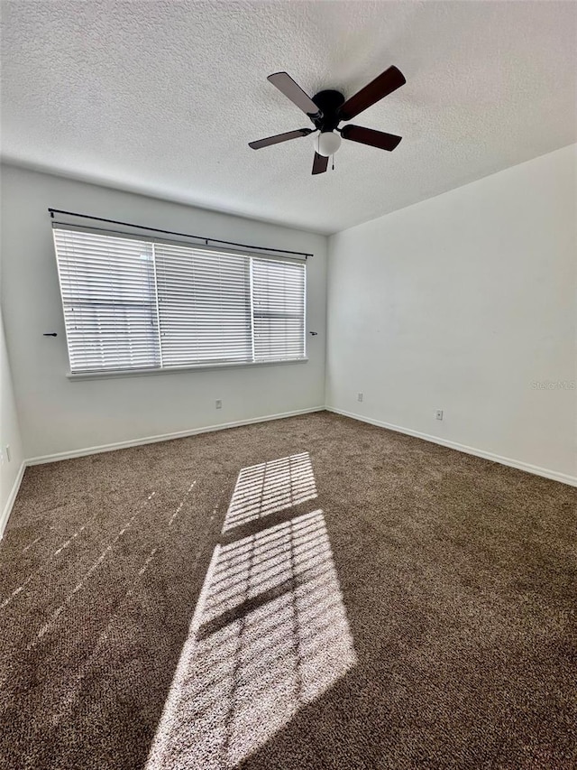 empty room with a textured ceiling, dark carpet, and ceiling fan