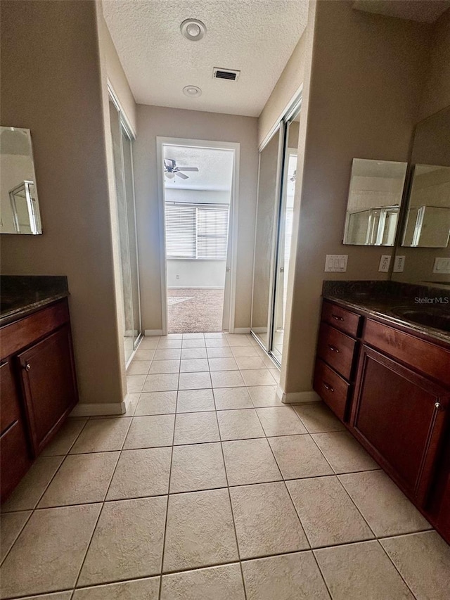 bathroom featuring tile patterned floors, vanity, an enclosed shower, and a textured ceiling