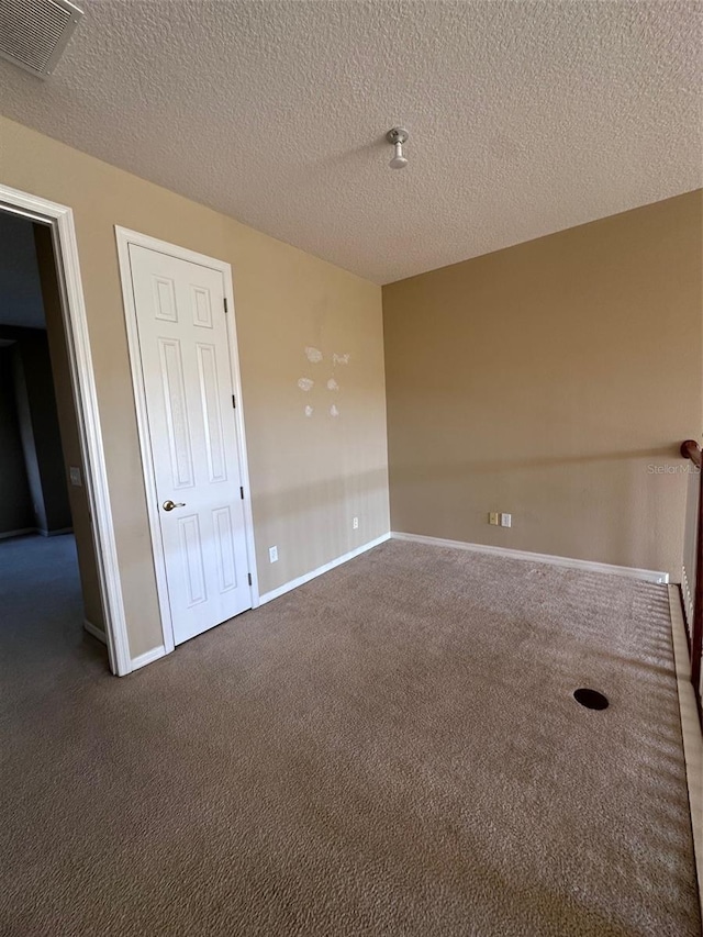 empty room with dark colored carpet and a textured ceiling