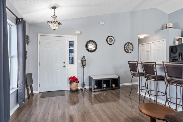 foyer entrance featuring a textured ceiling, dark hardwood / wood-style flooring, and vaulted ceiling