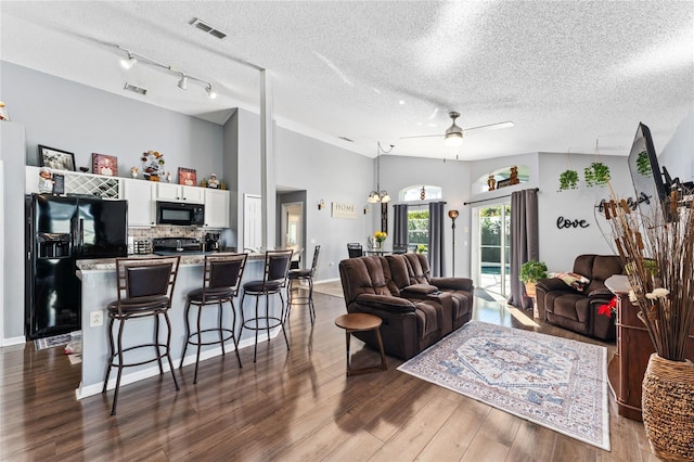 living room with a textured ceiling, hardwood / wood-style flooring, vaulted ceiling, and ceiling fan