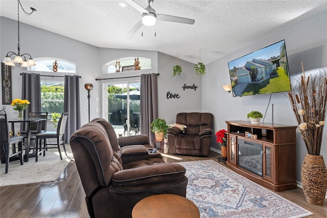 living room with a textured ceiling, ceiling fan with notable chandelier, dark wood-type flooring, and lofted ceiling