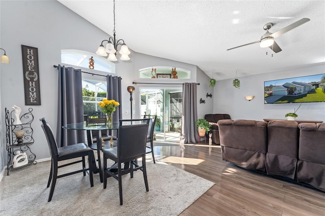 dining room featuring a textured ceiling, ceiling fan with notable chandelier, lofted ceiling, and hardwood / wood-style flooring