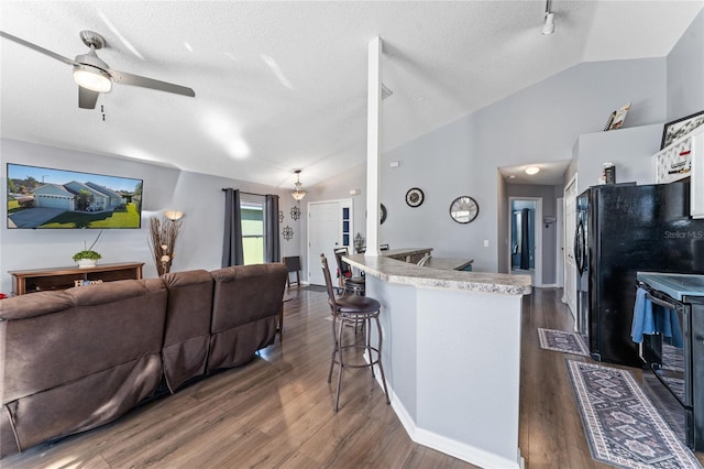 kitchen featuring a breakfast bar, vaulted ceiling, ceiling fan, and dark wood-type flooring