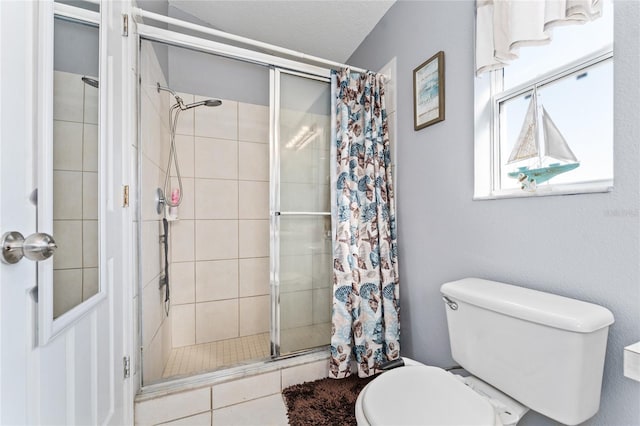 bathroom featuring a textured ceiling, toilet, and tiled shower