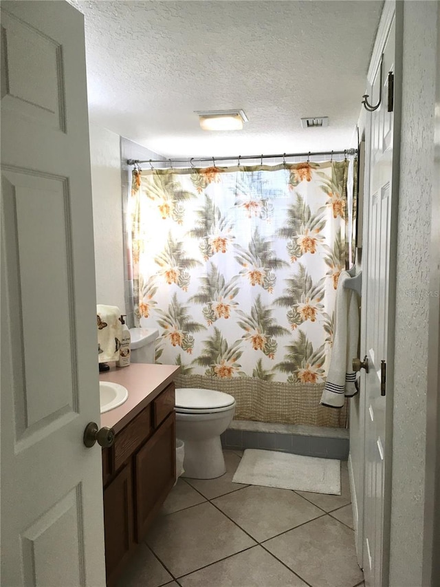 bathroom featuring curtained shower, tile patterned flooring, a textured ceiling, toilet, and vanity