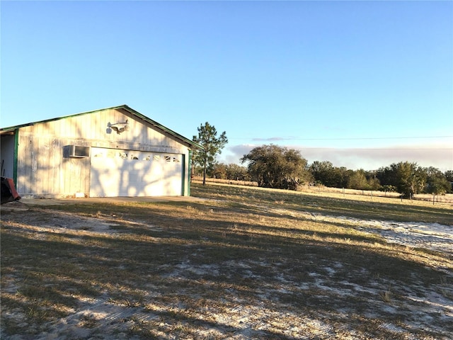 view of outdoor structure featuring a wall unit AC, a rural view, and a garage