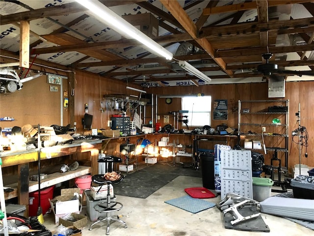 miscellaneous room with a workshop area, ceiling fan, concrete flooring, and wooden walls