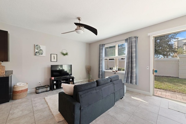 living room with a ceiling fan, baseboards, and light tile patterned floors