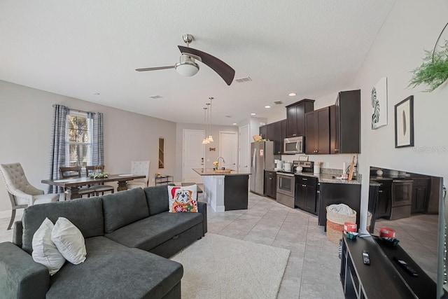 tiled living room with ceiling fan with notable chandelier and sink