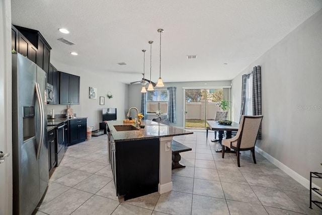 kitchen featuring dark stone counters, sink, an island with sink, a kitchen bar, and stainless steel appliances