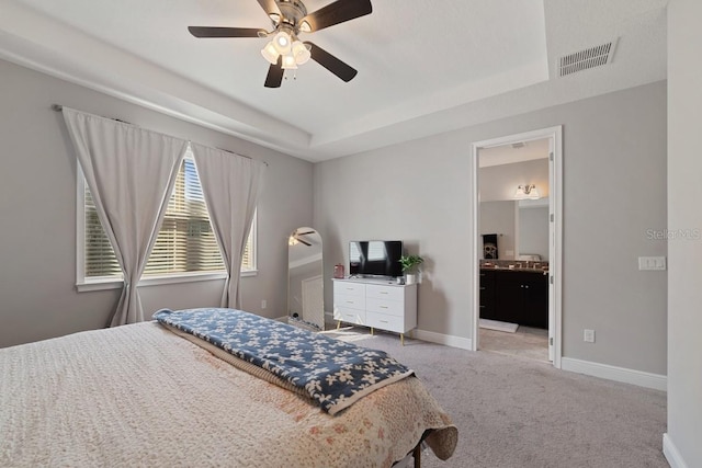 bedroom with light colored carpet, a raised ceiling, visible vents, and baseboards