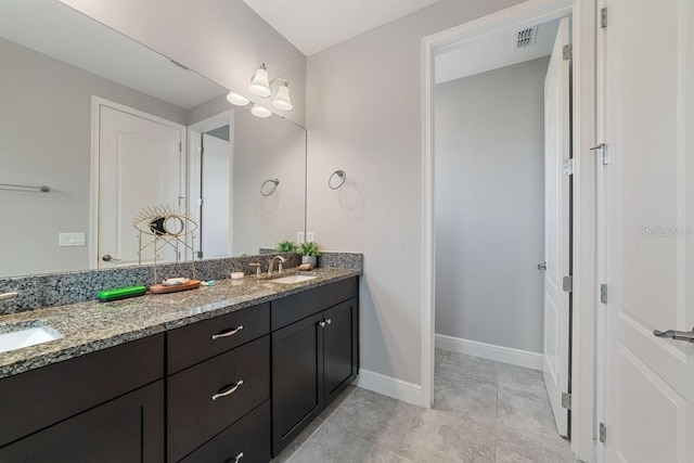 bathroom featuring visible vents, a sink, baseboards, and double vanity