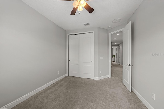 unfurnished bedroom featuring ceiling fan, light carpet, and a closet