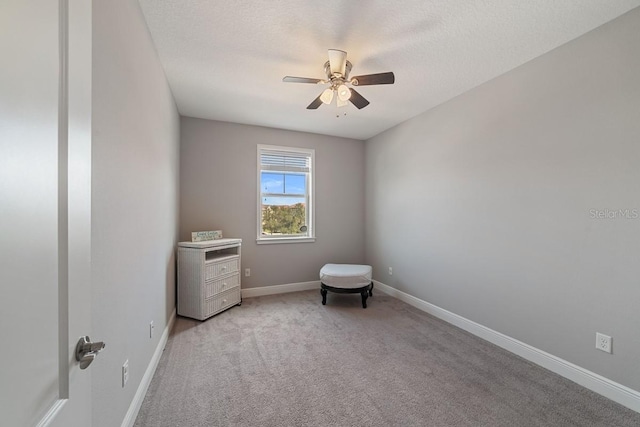 spare room featuring ceiling fan, baseboards, a textured ceiling, and light colored carpet