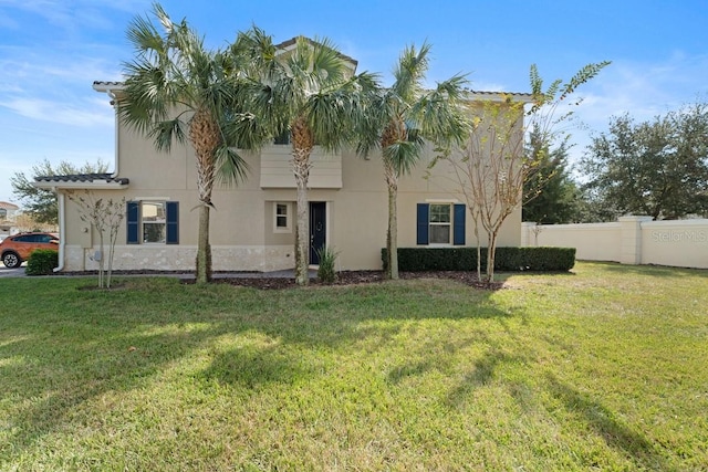 view of front of house with a front yard, fence, and stucco siding