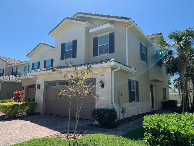 view of front of property with driveway, an attached garage, a tiled roof, and stucco siding