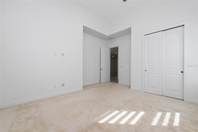 unfurnished bedroom with light carpet and a closet