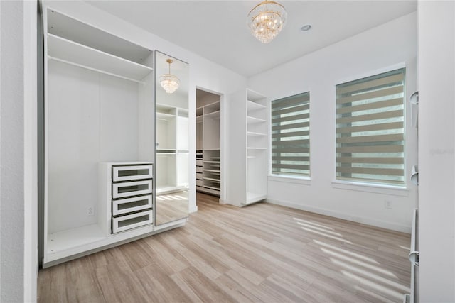 spacious closet with hardwood / wood-style flooring and a notable chandelier