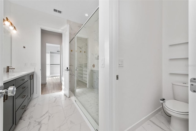 bathroom with tiled shower, vanity, and toilet