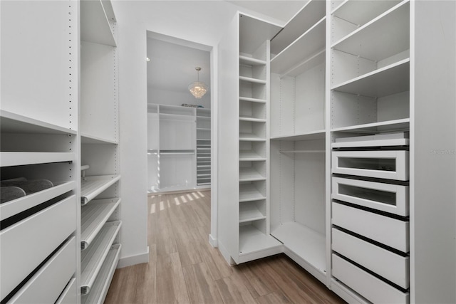 spacious closet featuring a chandelier and hardwood / wood-style floors