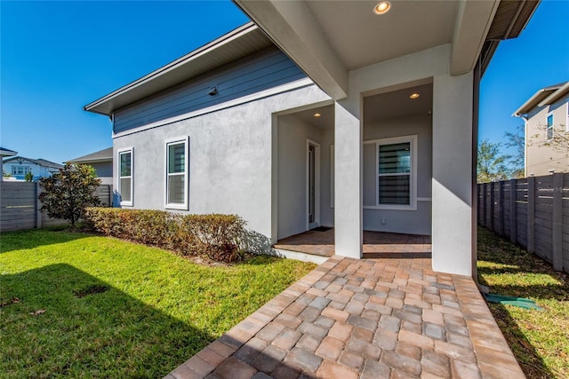 view of exterior entry featuring a patio area and a yard