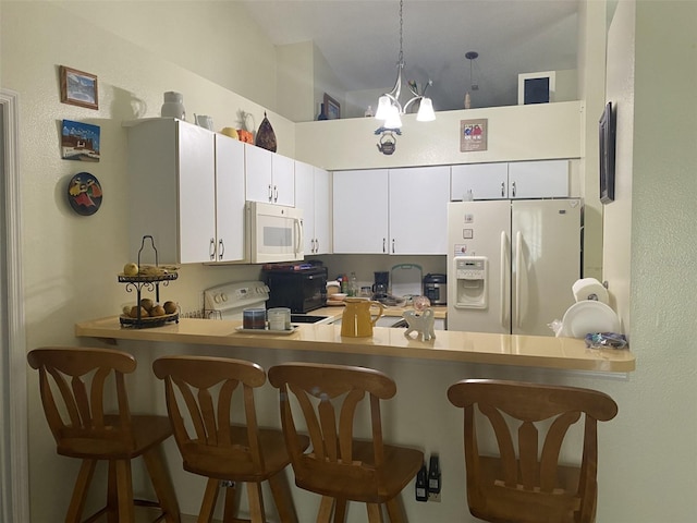 kitchen featuring a breakfast bar, white cabinetry, white appliances, and hanging light fixtures