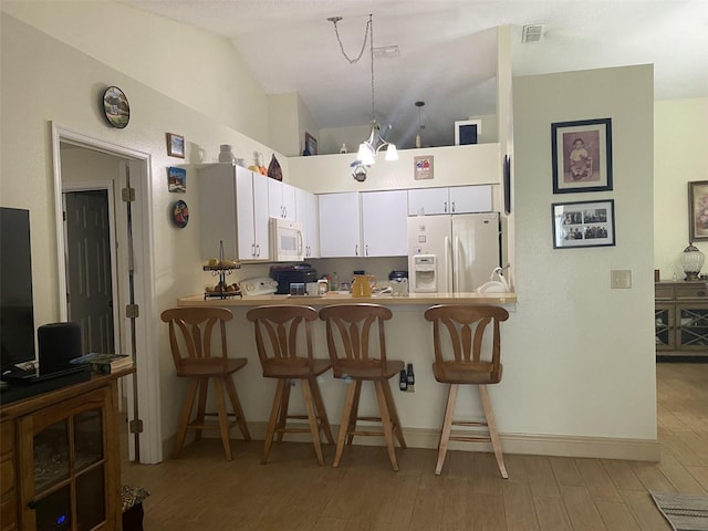 kitchen with white appliances, kitchen peninsula, vaulted ceiling, light hardwood / wood-style floors, and white cabinetry