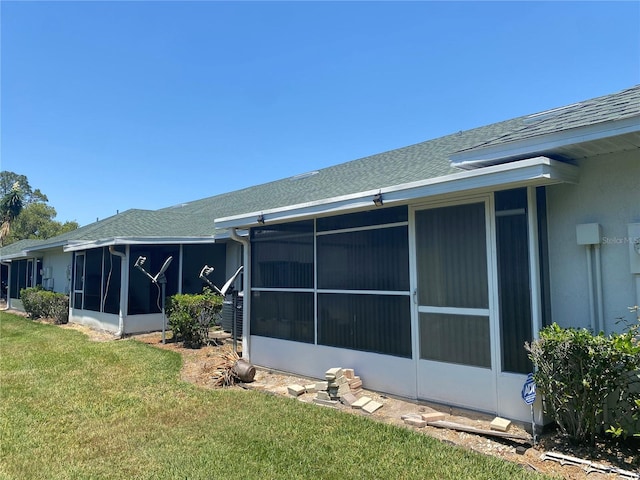 back of property with a yard and a sunroom