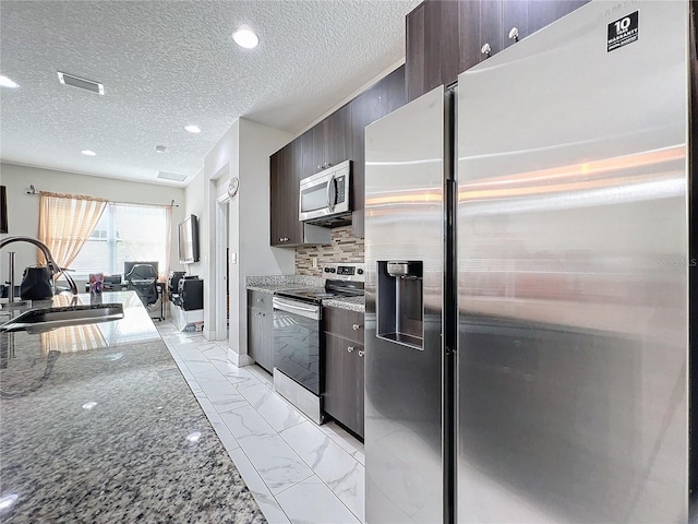 kitchen featuring dark brown cabinetry, light stone countertops, sink, and appliances with stainless steel finishes