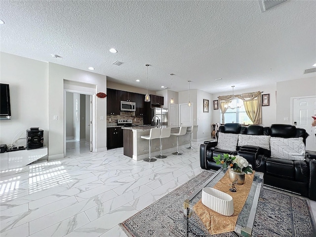 living room with a textured ceiling, an inviting chandelier, and sink