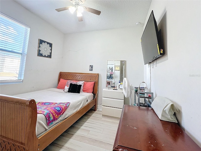 bedroom with ceiling fan, light hardwood / wood-style flooring, and a textured ceiling