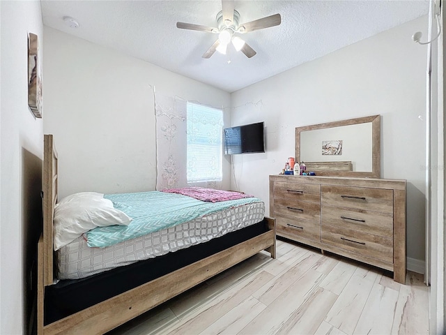 bedroom with a textured ceiling, light wood-type flooring, and ceiling fan