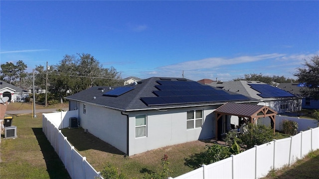 view of side of property with a gazebo, a lawn, cooling unit, and solar panels