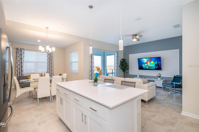 kitchen featuring stainless steel fridge, white cabinetry, a kitchen island, and decorative light fixtures