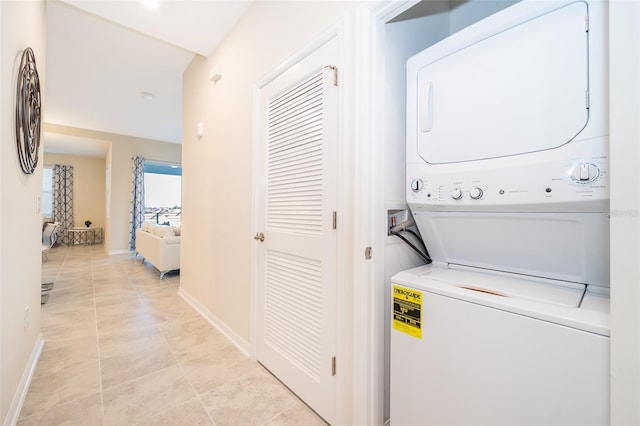 clothes washing area featuring light tile patterned floors and stacked washer and clothes dryer