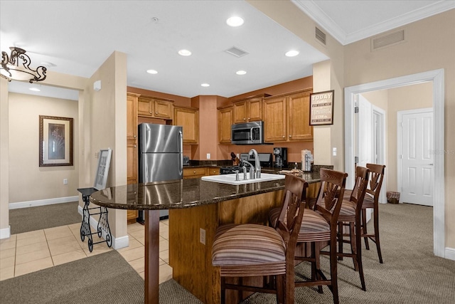 kitchen with a breakfast bar, light carpet, sink, ornamental molding, and stainless steel appliances